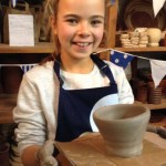 young girl uses the potters wheel to make a pot at eastnor pottery