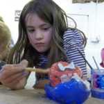 birthday girl paints her clay model at her birthday party at eastnor pottery herefordshire