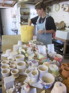 Workshop participants pots being glazed at Eastnor Pottery by pottery employee