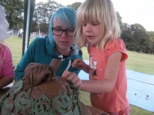 Lottie from Eastnor Pottery helps visitor make a giant Hfds cider apple