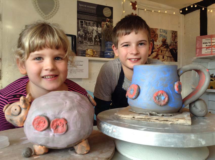 A brother and sister make a pottery piggy bank and wheel thrown mug at Eastnor Pottery as their Christmas present