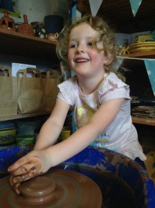 Young girl learning to make pottery on the potter's wheel at Eastnor Pottery